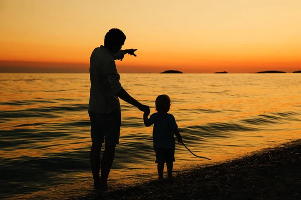 父と息子は浜辺の散歩シルエットをバックアップします。. — ストック写真