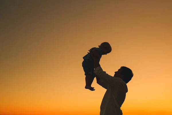 Vater und Sohn Silhouetten bei Sonnenuntergang am Strand. — Stockfoto