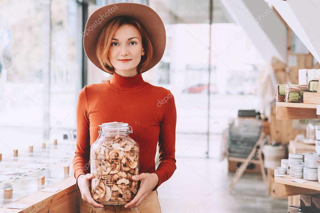 Woman holding glass jar with groceries in zero waste shop.