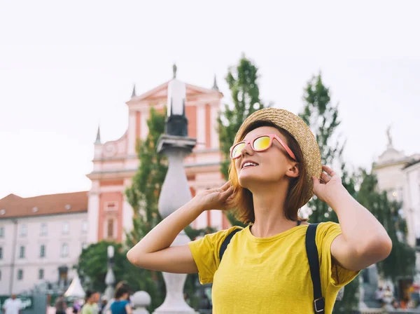 Young smiling girl in sunglasses in central square of Ljubljana Old Town at summer. Woman tourist on background of city architecture. Local living in Ljubljana. Travel or study in Slovenia, Europe.