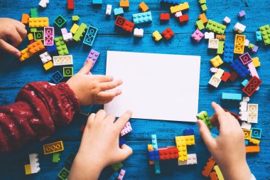 Çocuk elleri renkli oyuncak tuğlalarla oynuyor. Boş kartla ya da boş not defteriyle masaya plastik bloklar inşa etmek. Okul ya da anaokulu geçmişi. Çocuklar evde ya da sınıfta boş vakit ve eğitim.