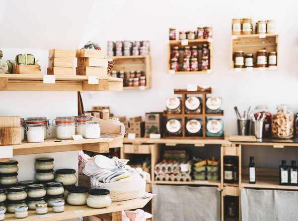 Zero waste shop interior details. Wooden shelves with different food goods and personal hygiene or cosmetics products in plastic free grocery store. Eco-friendly shopping at local small businesses