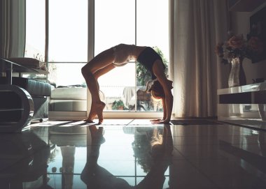 Evde yoga yapan genç bir kadın. Güzel bir kız meditasyon yapıyor ve evde yoga pozları veriyor. Sağlık vücudu ve zihin için kadın eğitimi. Stres yok, kadın mutluluğu, özgürlük, rahatla