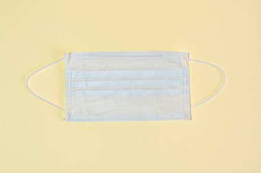 Sarı arka planda koruyucu tıbbi maske, üst tarafta yatıyordu..