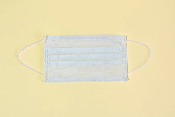 Protective medical mask on a yellow background flat lay top view. — Stock Photo, Image