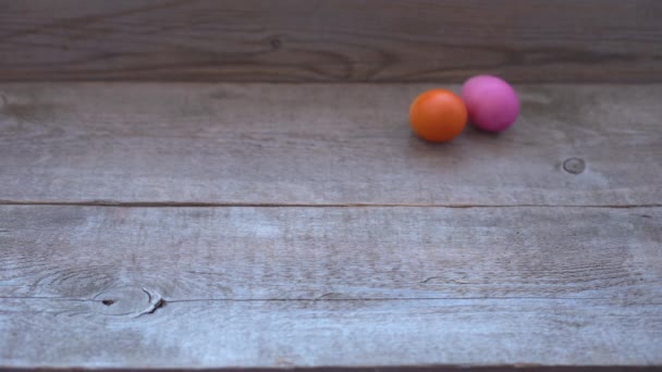 Huevos de Pascua de color rodar sobre una mesa de madera y rodar hacia atrás. Fondo concepto Pascua — Vídeo de stock