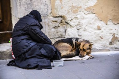 A beggar woman asks for alms with her dog.