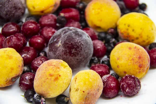 A Berry mix from frozen currant, apricot, plum, cherry. A Frozen Berries from freezer. A sweet background with frozen plum, currant, apricot and cherry. A healthy Berries on the background.