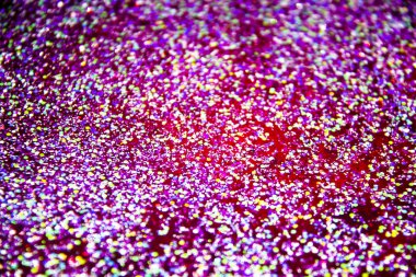 Işıltılı ve parıltılı soyut bir arka plan. Kırmızı sıvıda bir parıltı. Arkaplanda renkli simler.