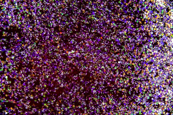 the abstract background with sparkles and glitters. A glitter in the red liquid. Colorful glitter on the background.