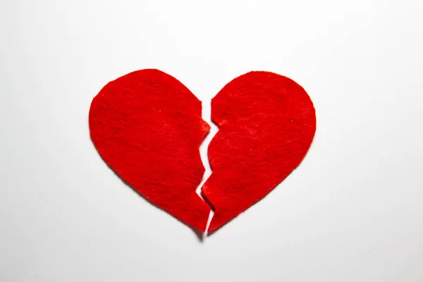 Broken red heart made of felt. Broken love concept.  A broken heart isolated on a white background. A  pain in my heart