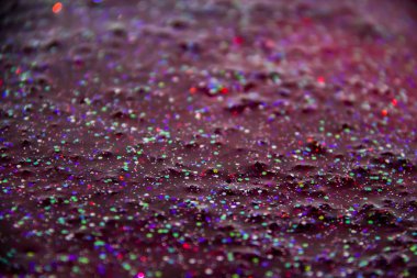 Kırmızı sıvıda bir parıltı. Renkli parıltılarla donatılmış çok güzel bir arka plan..