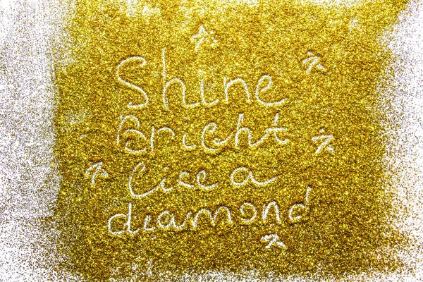 a composition with written a words shine bright like a diamond on beautiful gold glitter. Background and texture of gold glitter. Luxury gold glitter sparkle shining texture background