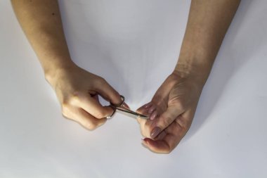 A composition of Women's hands which works with a manicure instrument against light background. Female hands make manicure. Concept with female hands.