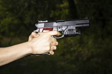 Karanlık bir arka planda silah tutan kadın eller. Silahlı tehlikeli bir durum.