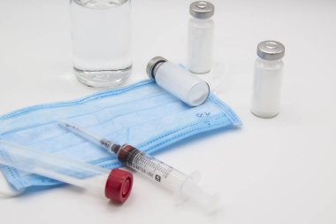 Masanın üzerinde tıbbi eşyalar ve şırıngalar var. Beyaz arkaplana karşı tıp kavramı