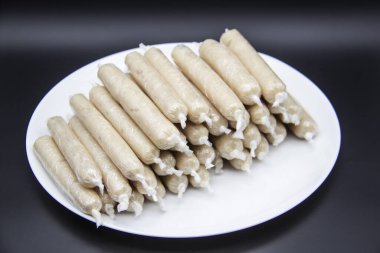 Tabakta GDO olmayan tavuk etinden yapılmış mis kokulu taze sosisler var. Ukrayna 'nın lezzetli yemekleri. Tabakta çiğ sosis var. Koyu arkaplanda bir sürü tavuk sosisi var.