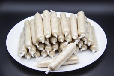 Tabakta GDO olmayan tavuk etinden yapılmış mis kokulu taze sosisler var. Ukrayna 'nın lezzetli yemekleri. Tabakta çiğ sosis var. Koyu arkaplanda bir sürü tavuk sosisi var.