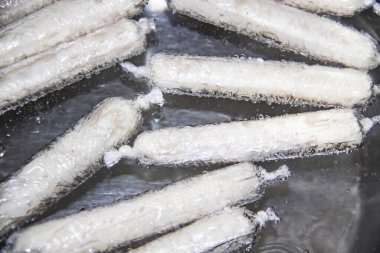 İşlem sıcak suda sosis kaynatıyor. Sıcak suyla birlikte tencerede GDO 'suz tavuk etinden yapılan mis kokulu taze sosisler. Ukrayna 'nın lezzetli yemekleri. Tencerede el yapımı sosisler..