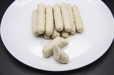 Tabakta GDO olmayan tavuk etinden yapılmış mis kokulu taze sosisler var. Ukrayna 'nın lezzetli yemekleri. Tabakta kaynamış el yapımı sosisler. Arka planda bir sürü tavuk sosisi var.