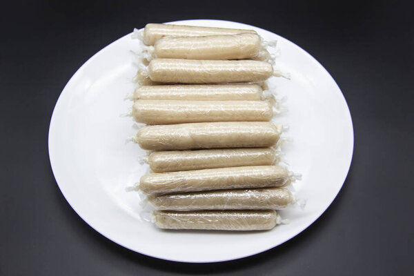 Ароматные свежие сосиски, сделанные из куриного мяса дома без ГМО на тарелке. Украинская вкусная еда. Сырые сосиски ручной работы на тарелке. Многие куриные сосиски на тарелке на темном фоне
