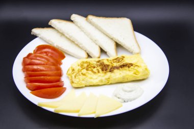 Lezzetli omlet, domates, peynir, ekmek ve sosla harika bir kahvaltı. Rulo gibi lezzetli omlet, diğer malzemeler. Lezzetli ve diyet yiyecekler. Kahvaltıda ya da öğle yemeğinde sağlıklı yemek.
