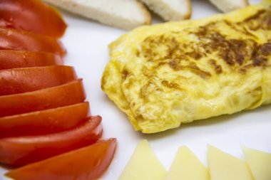Lezzetli omlet, domates, peynir, ekmek ve sosla harika bir kahvaltı. Rulo gibi lezzetli omlet, diğer malzemeler. Lezzetli ve diyet yiyecekler. Kahvaltıda ya da öğle yemeğinde sağlıklı yemek.