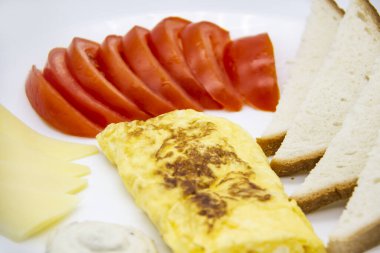 Lezzetli omlet, domates, peynir, ekmek ve sosla harika bir kahvaltı. Rulo gibi lezzetli omlet, diğer malzemeler. Lezzetli ve diyet yiyecekler. Kahvaltıda ya da öğle yemeğinde sağlıklı yemek.
