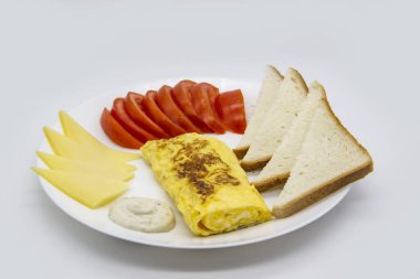 Lezzetli omlet, domates, peynir, ekmek ve sosla harika bir kahvaltı. Rulo gibi lezzetli omlet, diğer malzemeler. Lezzetli ve diyet yiyecekler. Kahvaltıda ya da öğle yemeğinde sağlıklı yemek.