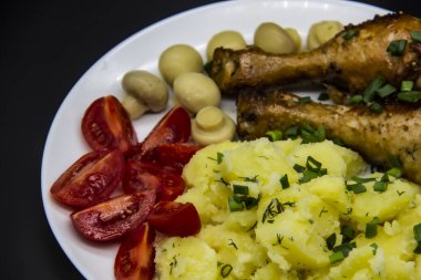 Lezzetli pişirilmiş tavuk budu, patates, domates, beyaz tabakta mantar. Akşam yemeğinde, öğle yemeğinde soğanlı ve dereotlu patates. Baharatta pişirilmiş harika tavuk bacakları. Ukrayna 'nın sağlıklı yemeği