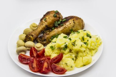 Lezzetli pişirilmiş tavuk budu, patates, domates, beyaz tabakta mantar. Akşam yemeğinde, öğle yemeğinde soğanlı ve dereotlu patates. Baharatta pişirilmiş harika tavuk bacakları. Ukrayna 'nın sağlıklı yemeği