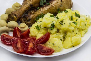 Lezzetli pişirilmiş tavuk budu, patates, domates, beyaz tabakta mantar. Akşam yemeğinde, öğle yemeğinde soğanlı ve dereotlu patates. Baharatta pişirilmiş harika tavuk bacakları. Ukrayna 'nın sağlıklı yemeği