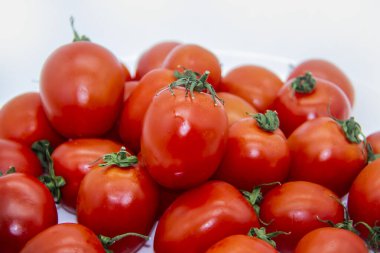 Beyaz arka planda beyaz bir tabakta taze kırmızı domatesler. GDO 'suz güzel ve sağlıklı vişneli domatesler..