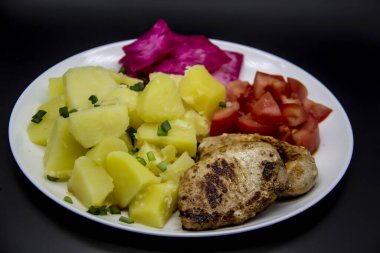 Patatesli mini biftekler, domatesler ve beyaz tabakta Pelyustka adında lahana turşusu. Etli sağlıklı kahvaltı, haşlanmış patates, domates ve kırmızı lahana turşusu. Öğle yemeği için nefis yemek.