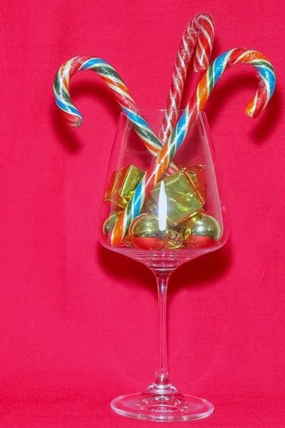 Copo de vinho com decorações de Natal em um fundo vermelho — Fotografia de Stock