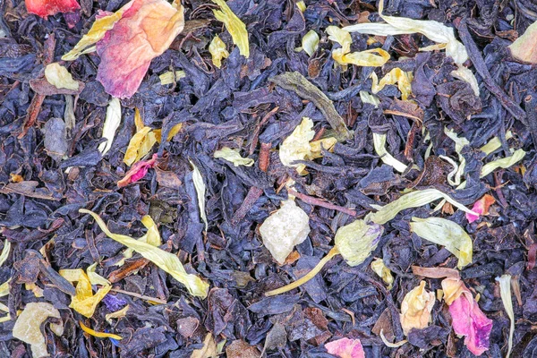 Meyve parçaları ve çiçek yapraklı siyah çay.