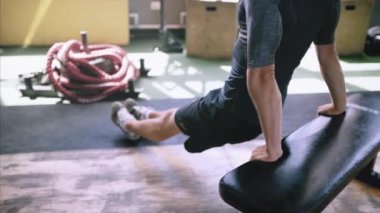 Formda ve formda bir adam spor salonundaki bankta triseps dalışı yapıyor..