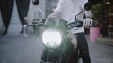 Bisikletçi deri eldiven ve siyah kapüşonlu motosiklet başlar.