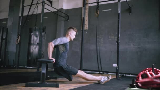 Muž v dobré kondici dělá triceps namáčení cvičení na lavičce v tělocvičně. — Stock video