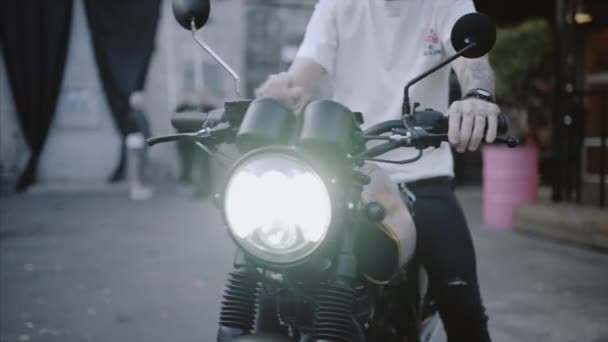 Motociclista en guantes de cuero y sudadera con capucha negro inicia motocicleta . — Vídeos de Stock