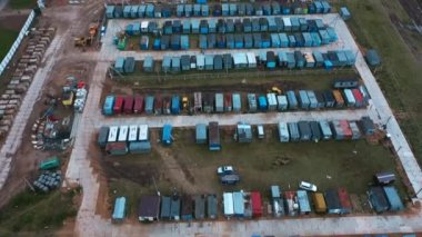 İHA, inşaat işçileri ve bekçiler için kırmızı ve mavi prefabrik kulübelerin üzerinde uçuyor.