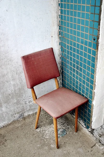 an old chair stands in the corner of the balcony