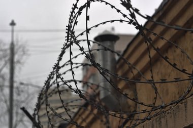 barbed wire fencing over a beige brick wall