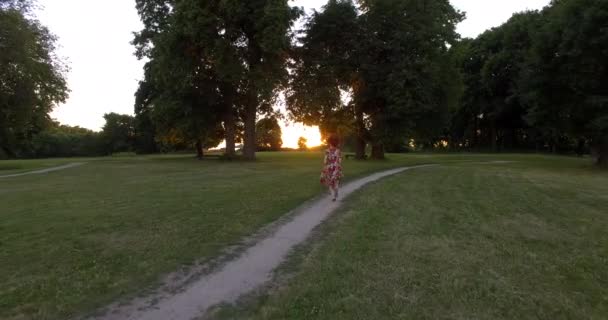 Vonzó játékos lány fut felé naplemente napfény. Légi drónkövető lövés. — Stock videók