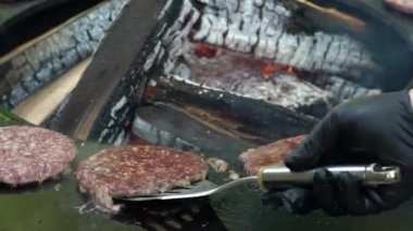 Elleri yukarıda, ızgarada hamburger eti kızartıyorlar. El kamerasıyla.