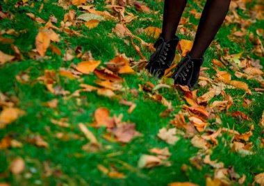 Sonbahar yaprakları, yeşil çimlerde yürüyen bir kız, sarı yapraklar, çizmeler.