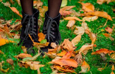 Sonbahar yaprakları, yeşil çimlerde yürüyen bir kız, sarı yapraklar, çizmeler.