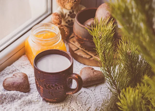 Breakfast on the windowsill: cocoa, cookies and orange jam. Sprig of green pine.Heart shaped cookies