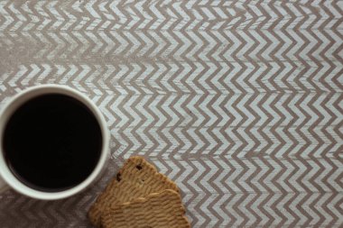 Kahve fincanı ve kurabiyeler zigzag arka planda, doku arka planında, yukarıdan çekilmiş..