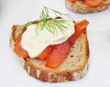 Taze kremalı ve dereotlu tost üzerine tütsülenmiş somon balığı Gravlosu. Gravlax Norveçli, İsveçli ya da Danimarka usulü ince dilimlenmiş ve yanında dereotu ve hardal sosu bulunan bir somondur.